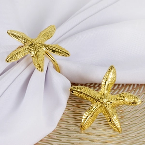 Close-up of golden starfish napkin ring showing textured finish on white fabric