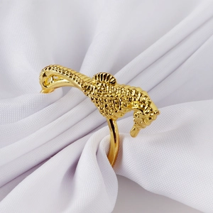 Macro shot of a detailed golden seahorse napkin ring on white satin fabric texture