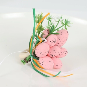 Detail of Easter napkin ring with pink speckled eggs and artificial flowers on wood