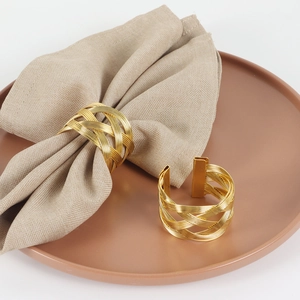 Irregular gold woven metal napkin rings set on a ceramic plate with linen napkins
