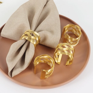 Set of 4 gold irregular woven metal napkin rings displayed on a brown ceramic plate