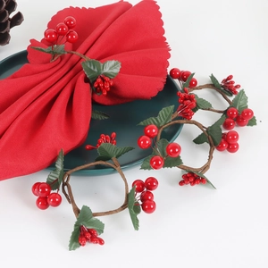 Handmade Christmas napkin rings with realistic red berries and green leaves on red napkins