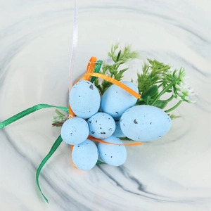 Close-up of Easter egg napkin ring with blue speckled eggs and green leaves on marble