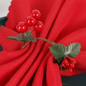 Christmas napkin ring with red faux berries, green leaves and brown vine on a red napkin
