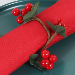 Close-up of artificial red berry napkin ring with green leaves on festive table setting