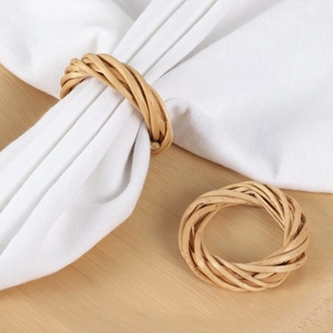 Handwoven natural rattan napkin rings set of two on a wooden table with white linen