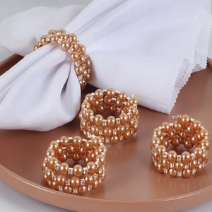 Gros plan de ronds de serviette en perles champagne tressées avec strass brillants