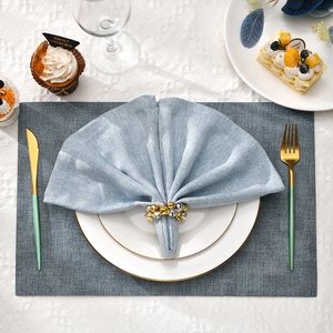 Elegante kersttafel met goud-zilveren belletjes servetringen op lichtblauw linnen servet