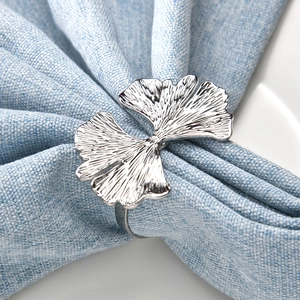 Rond de serviette élégant en feuille de ginkgo argentée sur tissu bleu et assiette