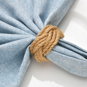 Minimalist woven jute napkin ring with natural twine texture on blue linen fabric