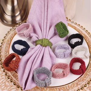 Handmade woven napkin rings in multiple colors displayed on a luxury ceramic tray