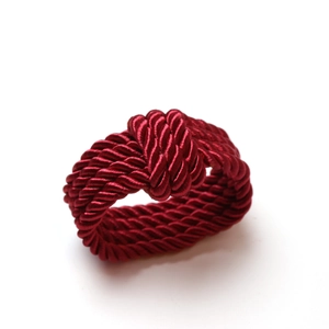 Macro detail of wine red handcrafted woven rope napkin ring with braided texture