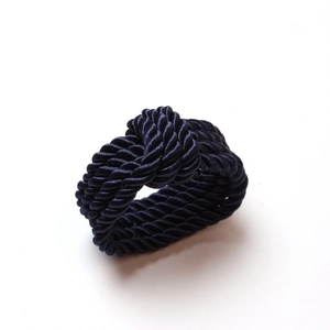 Detail of burgundy woven napkin ring featuring a glossy spiral braided rope texture