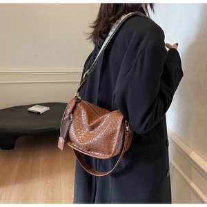 Détail du sac hobo en cuir tressé marron montrant la texture entrelacée et la bandoulière