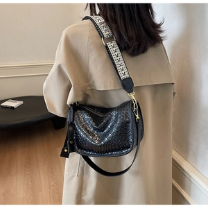Détail de la texture en cuir noir tressé et de la bandoulière large à motifs