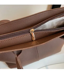 Detailed close-up of smooth gold zipper and pebble leather texture on a brown tote bag