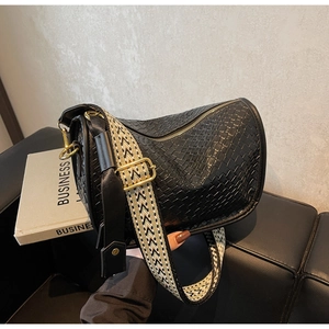 Détail du sac Boston noir tressé avec bandoulière géométrique et finitions dorées