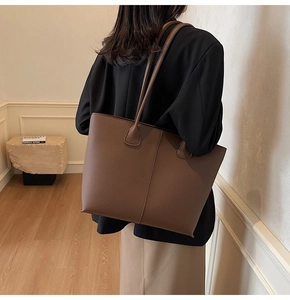 Detailed back view of a large dark brown lychee leather tote bag worn by a model