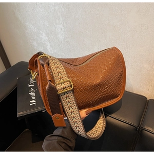 Détail du sac baguette en similicuir marron avec texture tissée et bandoulière