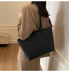 Close-up of a large black tote bag with lychee texture and vertical stitching detail