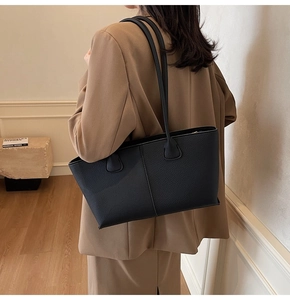 Close-up of black lychee-grain tote bag with fine stitching on minimalist shoulder straps