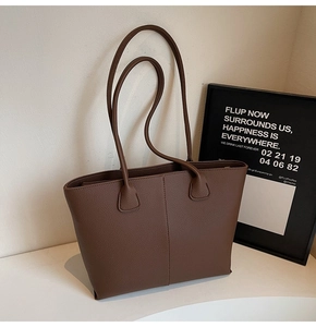 Detail view of deep brown pebbled leather tote bag with vertical seam and dual straps
