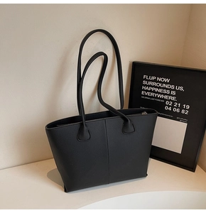 Close-up of black pebbled leather tote bag showing detailed texture and vertical stitching