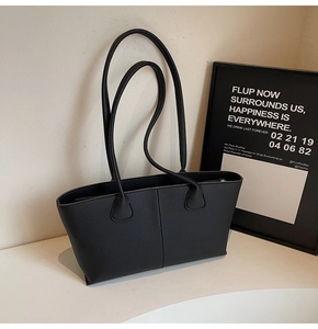 Close-up of minimalist black lychee grain leather tote bag with elegant vertical stitching