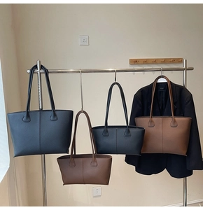 Detail view of large and small tote bags in black and caramel brown pebbled leather