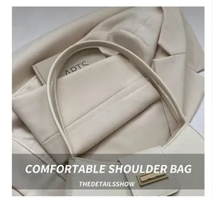 Detail of a creamy white leather shoulder bag featuring a gold rectangular metal buckle