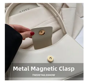 Detailed macro of the white leather bag featuring its premium magnetic closure hardware