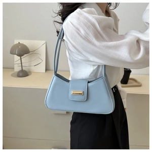 Detail of light blue baguette bag with gold buckle on a minimalist indoor background