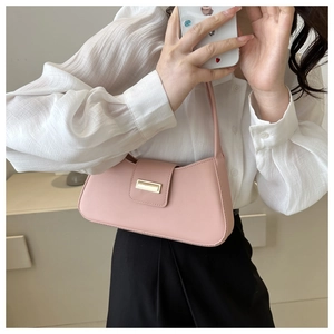 Detail of pink French-style baguette bag with metal buckle on slim shoulder strap
