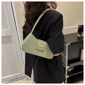 Model wearing a sage green matte leather baguette bag with a gold rectangular buckle