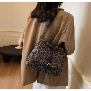 Dettaglio della borsa leopardata con tracolla in pelle nera e fibbia dorata su modella