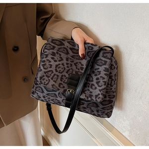 Dettaglio della borsa a tracolla leopardata con cinturino in pelle nera e fibbia dorata