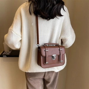 Vintage brown leather messenger bag with top handle and shoulder strap shown on model