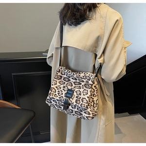 Dettaglio della borsa tote leopardata con cinturini in pelle nera indossata dal modello