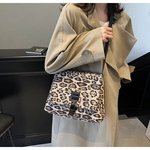 Dettaglio borsa leopardata con cinturino nero indossata su un trench beige stile moderno