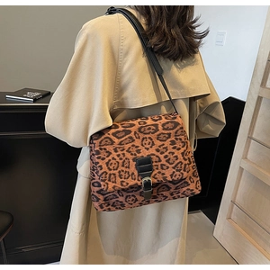 Dettaglio della borsa a tracolla leopardata con cinturino nero su cappotto beige