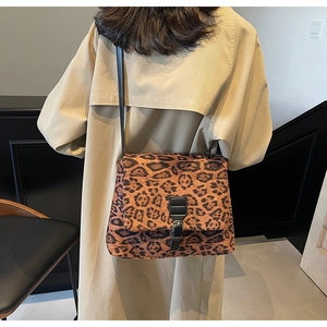 Dettaglio di una borsa a spalla leopardata abbinata a un elegante trench coat beige