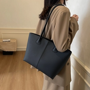 Black minimalist faux leather tote bag with lychee texture shown on a female model