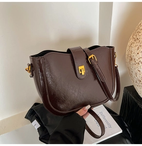 Detailansicht der dunkelbraunen glänzenden Eimer-Tasche mit goldener Metallschnalle
