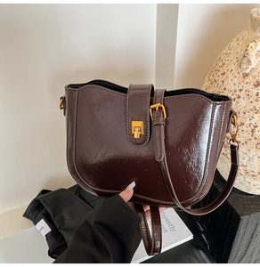 Nahaufnahme der dunkelbraunen Vintage-Satteltasche mit glänzendem Leder und Goldverschluss