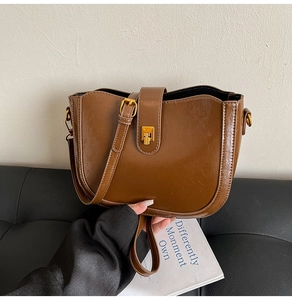 Nahaufnahme der braunen glänzenden Beuteltasche mit goldenem Verschluss und Lederstruktur