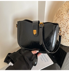 Detailansicht der schwarzen glänzenden Eimer-Tasche mit goldenen Metallbeschlägen