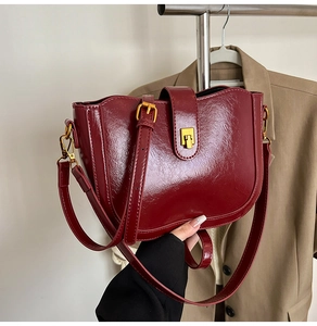 Detail einer dunkelroten Ölwachs-Leder-Eimertasche mit goldener Schnalle und Gurt