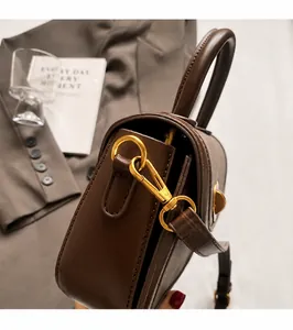 Detailed close-up of premium gold-tone metal hardware and D-ring on dark brown saddle bag