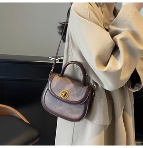 Detail of a vintage contrast saddle bag featuring a gold twist lock and leather strap