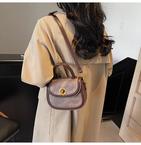 Detail of vintage saddle bag with brown suede patchwork and gold buckle on beige trench coat
